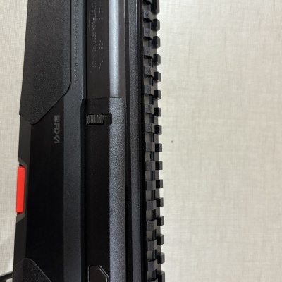 Parte de uma arma preta com montagem rail e texto em relevo