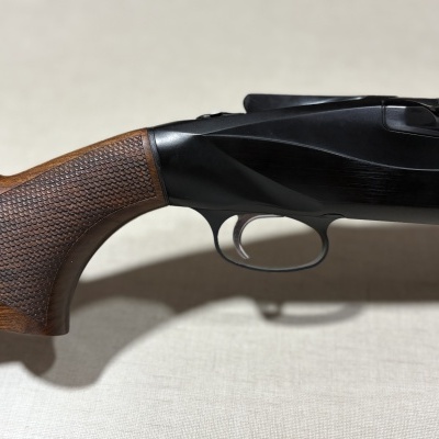 Parte da espingarda com coronha de madeira castanha e corpo preto com número 828