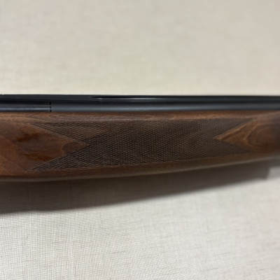 Espingarda com coronha em madeira castanha e canos pretos.