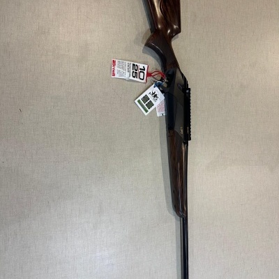 Espingarda com coronha de madeira castanho escuro e cano preto com etiquetas penduradas