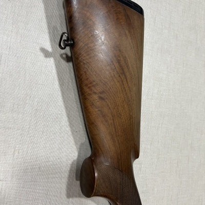 Coronha de espingarda em madeira castanha polida sobre tecido claro