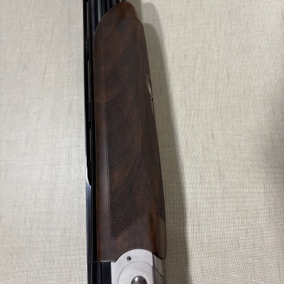 Espingarda Beretta com punho em madeira castanha texturizada e metal prateado