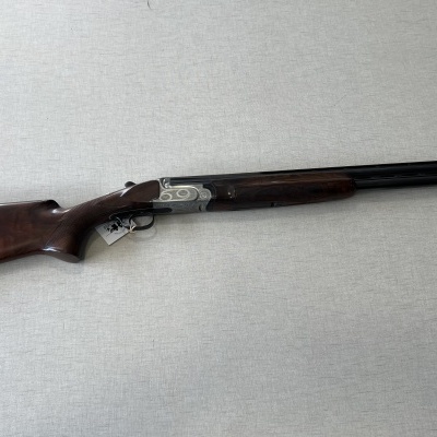 Espingarda de canos duplos com madeira castanha e metal preto sobre fundo cinza claro