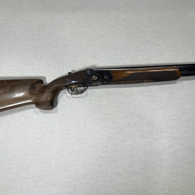 Espingarda de canos duplos com coronha em madeira escura sobre superfície clara
