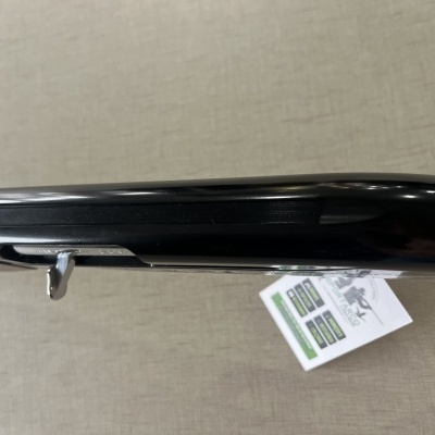 Espingarda com acabamento em metal preto e cabo de madeira sobre superfície cinzenta