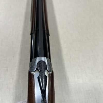 Espingarda de cano duplo em metal preto e madeira castanha vista de cima