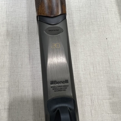 Parte de espingarda Benelli com cabo em madeira e corpo metálico cinzento fosco, texto gravado