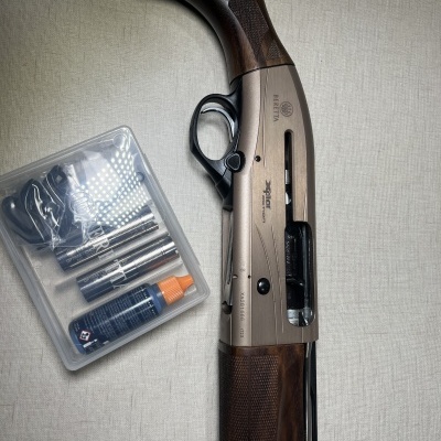 Espingarda Beretta A300 Outlander com acessórios em caixa transparente ao lado