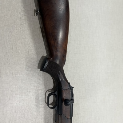 Espingarda com coronha em madeira escura e metal preto contra fundo branco