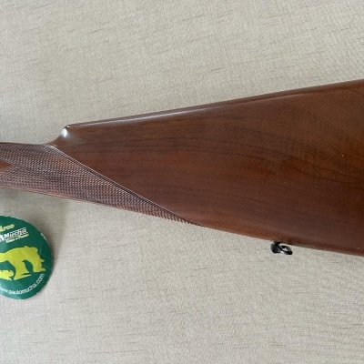 Coronha de madeira polida de espingarda com etiqueta verde e amarela pendurada