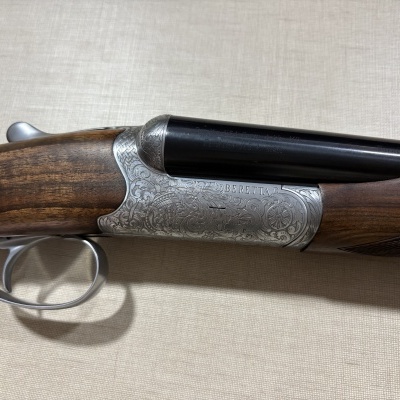 Espingarda dupla com detalhes em madeira e metal gravado.