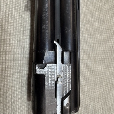 Parte de arma de fogo metálica preta e prateada com texto gravado