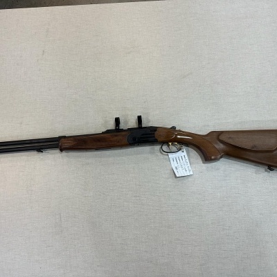 Espingarda de metal negro com coronha em madeira castanha sobre superfície clara