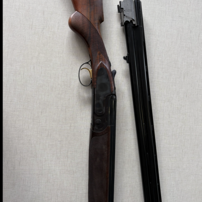 Espingarda de caça de madeira e metal em duas partes separadas em fundo cinzento.