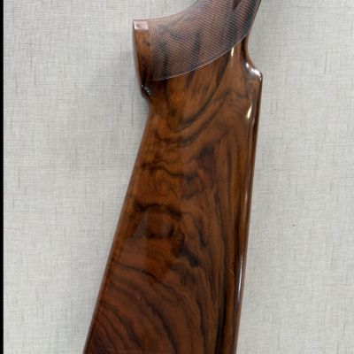 Coronha de espingarda em madeira polida com textura no punho.