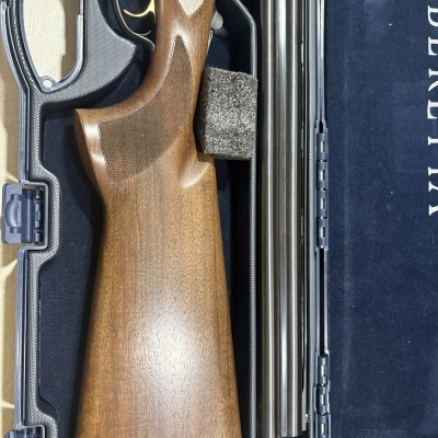 Espingarda com madeira castanha e canos metálicos num estojo de veludo azul