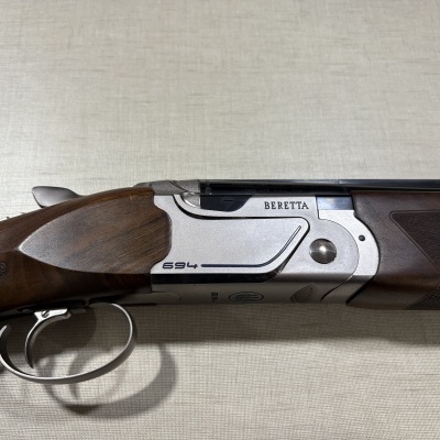 Espingarda Beretta 694 em metal e madeira sobre superfície cinza-clara