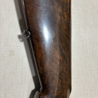 Espaço traseiro de arma de fogo em madeira castanha polida com detalhe em pele preta