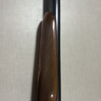 Parte frontal de arma de fogo com madeira castanha e metal preto