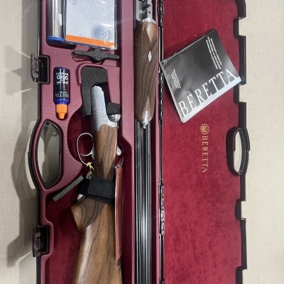 Estojo vermelho com espingarda Beretta desmontada e acessórios.