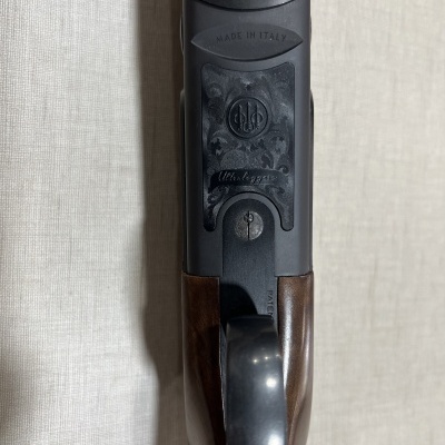 Parte superior de espingarda em madeira e metal com inscrições e logo