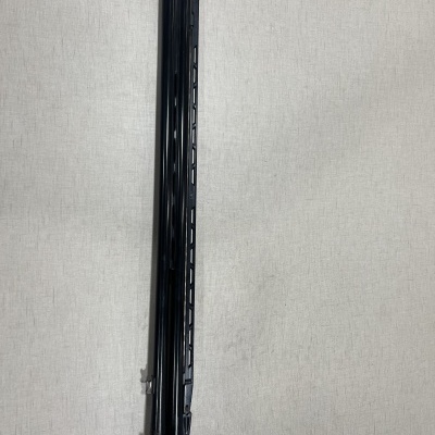 Objeto longo preto com detalhes cinzentos sobre fundo claro texturizado