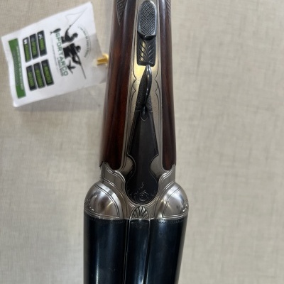 Espingarda de canos duplos com coronha em madeira castanha escura e acabamento metálico prateado