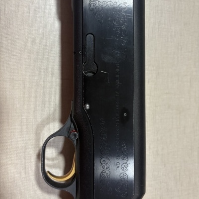 Caixa mecânica preta com gravações e texto de arma sobre fundo bege