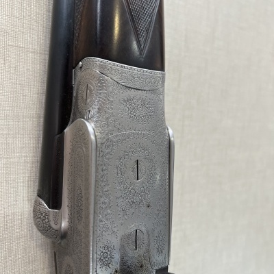 Espingarda de caça com detalhes gravados em metal e cabo de madeira