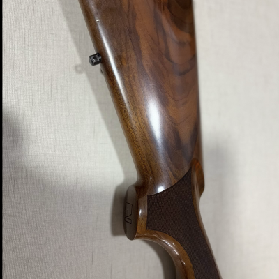 Coronha de arma de fogo em madeira polida castanha com textura na empunhadura.