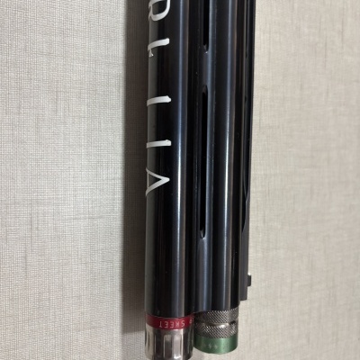 Pontas pretas de canos com inscrições brancas e anéis vermelho e verde, sobre fundo bege texturizado.