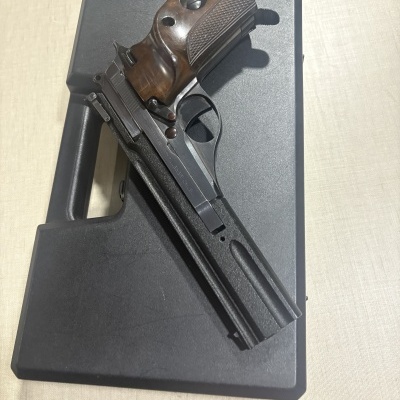 Revólver ou pistola com empunhadura de madeira e corpo metálico preto sobre caixa preta