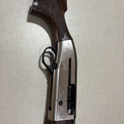 Parte de arma com punho em madeira castanha e corpo metálico prateado gravado