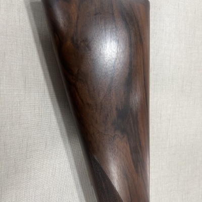 Ponteira de arma de fogo em madeira polida com textura às extremidades