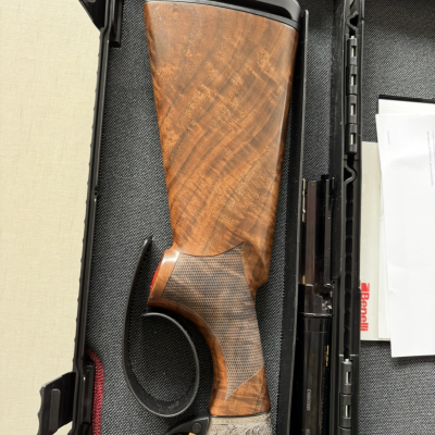 Espingarda com coronha em madeira e detalhes metálicos numa mala de transporte preta.