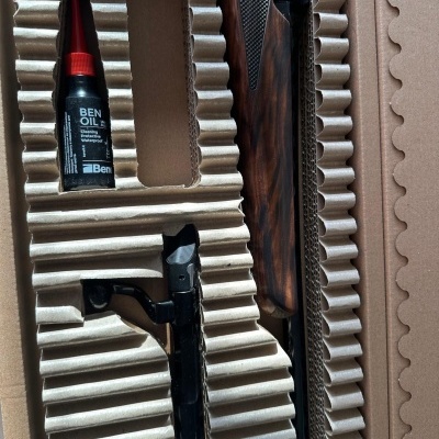 Embalagem com espuma moldada contendo madeira escura, peça metálica preta e frasco BEN OIL