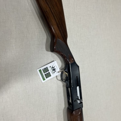 Espingarda com coronha de madeira e armação metálica preta sobre superfície clara