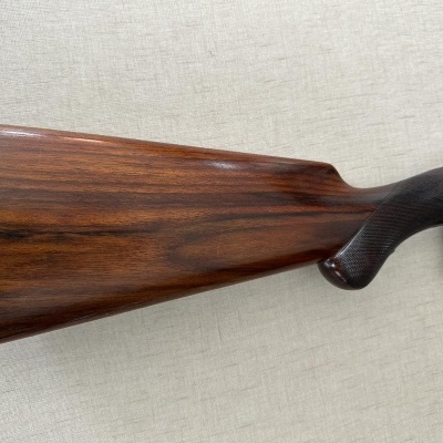 Coronha de espingarda em madeira castanha escura com acabamento brilhante e bocado preto