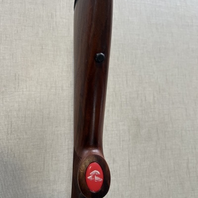 Arma de madeira com botão vermelho e símbolo branco