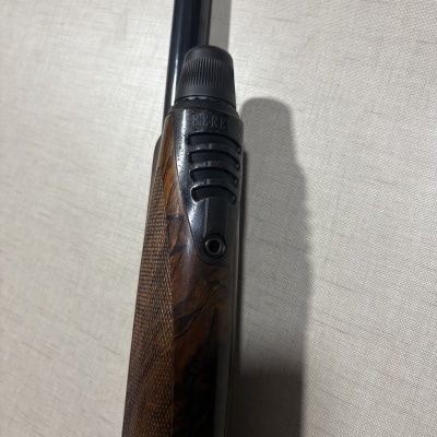 Parte de espingarda com madeira castanha e metal escuro sobre tecido claro