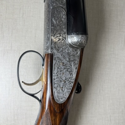 Espingarda de caça com detalhes gravados em metal e cabo em madeira