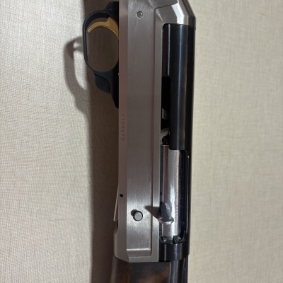 Parte de arma de fogo com punho em madeira, caixa metálica prateada e gatilho dourado