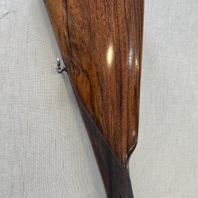 Coronha de arma de fogo em madeira polida castanha com textura natural e detalhes texturizados.