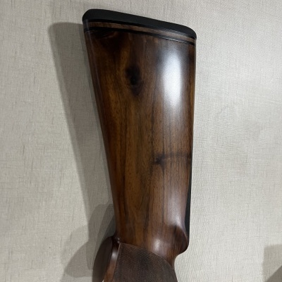 Coronha de espingarda em madeira escura com topo em borracha preta sobre tecido bege