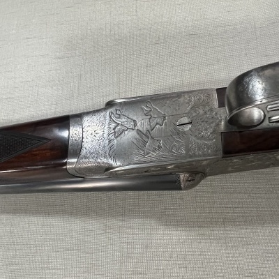 Espingarda de canos duplos com gravuras de caça na caixa de metal e coronha de madeira escura