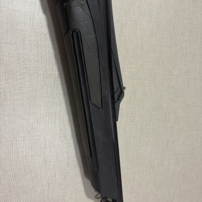 Parte de arma de fogo preta com inscrição contra fundo bege texturizado