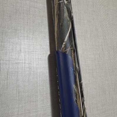 Arma de fogo com padrão camuflado e detalhes azuis contra fundo cinza texturizado