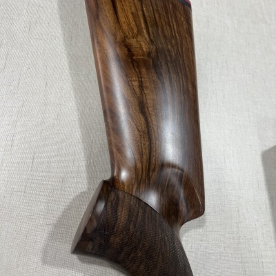 Peça de madeira polida com acabamento vermelho na borda, sobre tecido bege claro