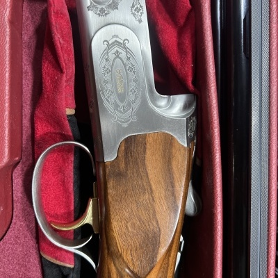 Parte de uma espingarda com madeira polida e metal cinza gravado no estojo vermelho