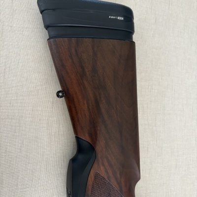 Parte traseira de arma com madeira e borracha preta e texto KICK-OFF